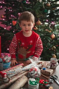 Un enfant se tient près d'un arbre de Noël et de cadeaux.