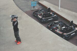 personne portant un casque debout à côté de deux karts