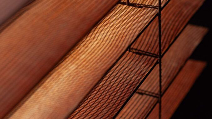 Lames de bois et grille métallique sous lumière tamisée