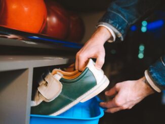 Une main retire une chaussure de bowling verte d'un seau bleu