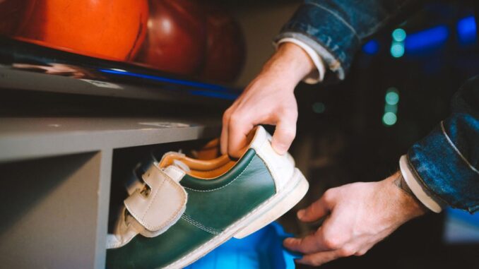 Une main retire une chaussure de bowling verte d'un seau bleu