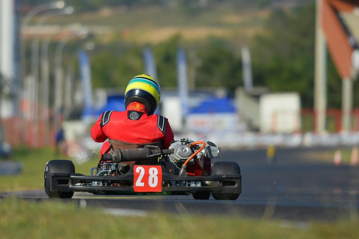 Un coureur en combinaison rouge et casque pilote un kart