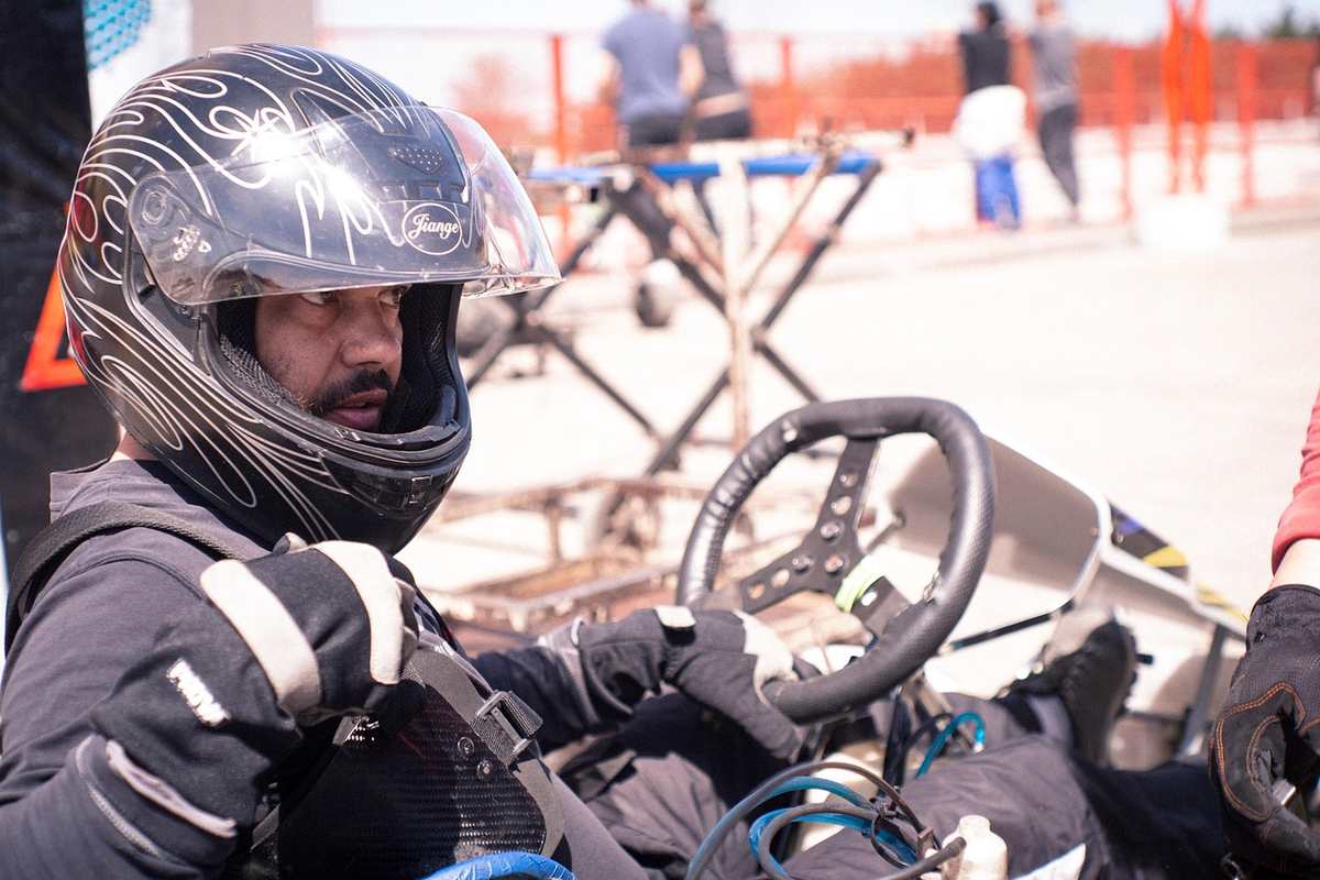 Un homme avec un casque noir conduit un kart sur un circuit