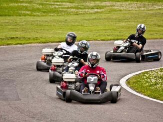 Quatre conducteurs en karting tournent sur un virage de piste